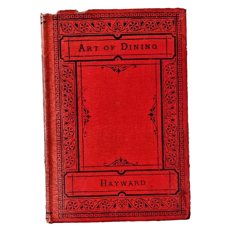 A vintage red hardcover book titled 'Art of Dining' by Hayward, featuring an ornate black decorative border and a textured linen-like cover.