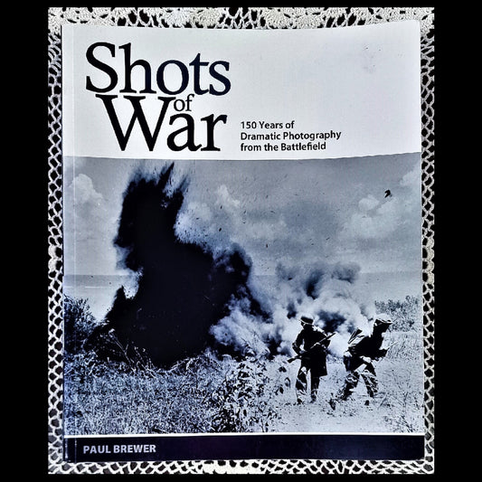 The cover of the book 'Shots Of War: 150 Years Of Dramatic Photography From The Battlefield' displays a black and white image of soldiers in action during a war, indicating the book's focus on dramatic photography of historical events.