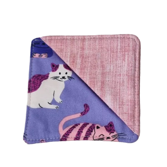 A square fabric bookmark with a diagonal split design, featuring a pink textured fabric on one side and a lavender purple fabric on the other with printed cat illustrations.