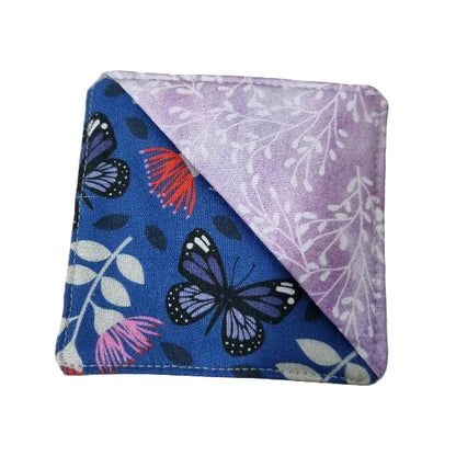 A fabric bookmark with a diagonal split design, featuring a blue side with black and purple butterflies, pink flowers, and white leaves, and a lavender side with white floral patterns.