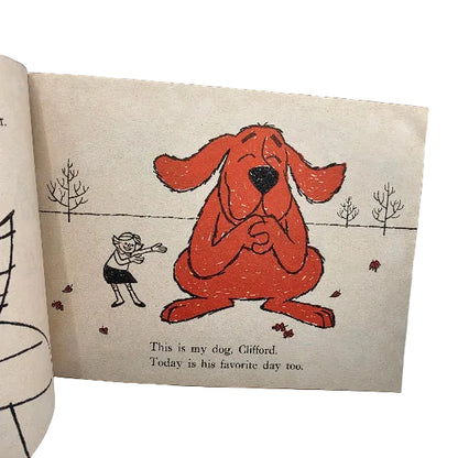 A vintage children's book page featuring a hand-drawn illustration of Clifford, the red dog, sitting on beige paper with printed text below reading, 'This is my dog, Clifford. Today is his favorite day too.