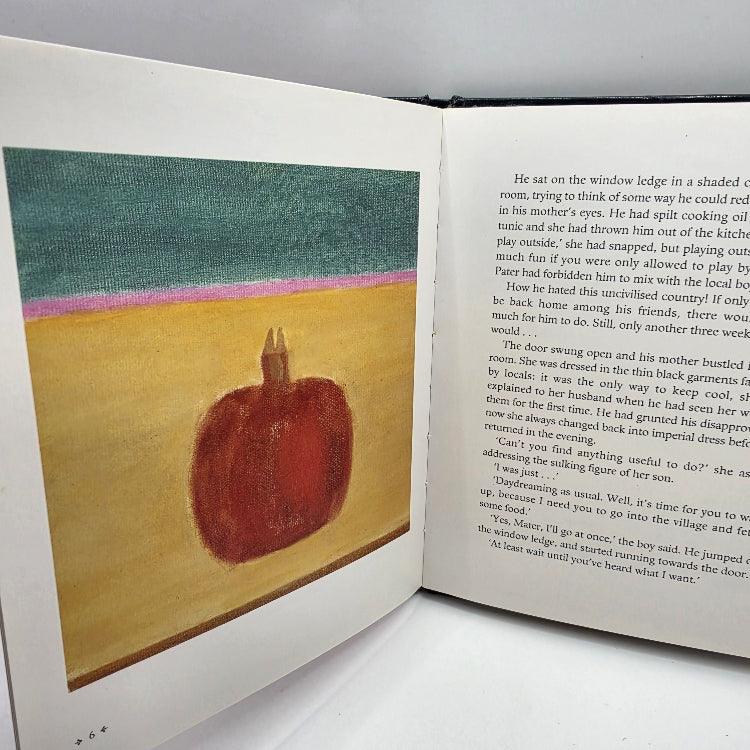 An open book showing a printed page with a small illustration of a reddish-brown apple against a sunset sky with green, pink, and orange tones.
