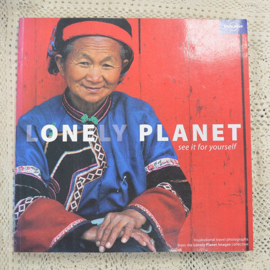 Lonely Planet travel photography book featuring a portrait of an elderly woman in traditional blue and red clothing against a red wooden background.