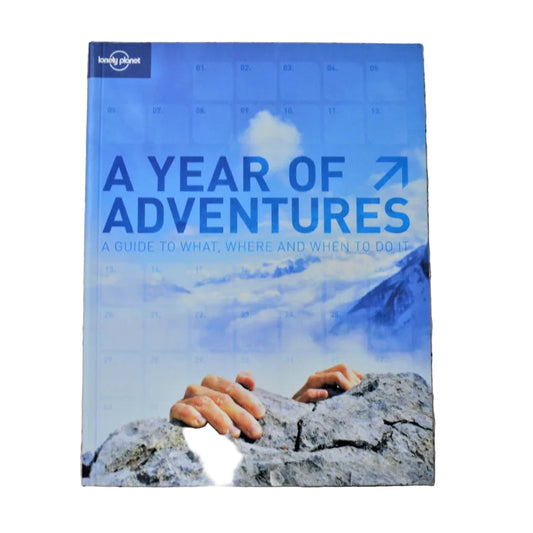 A paperback book titled 'A Year of Adventures' by Lonely Planet Publishing, featuring a mountain and sky cover image.